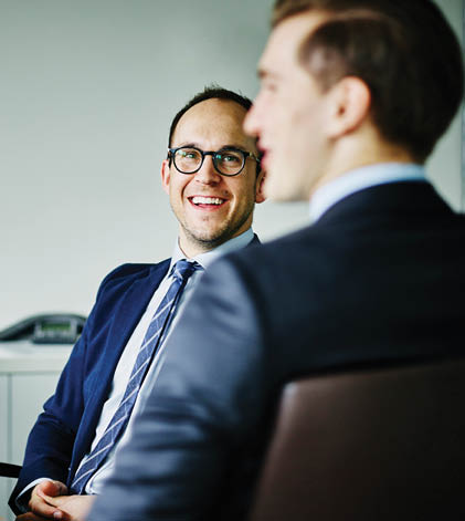 Business men sitting in a meeting smiling.