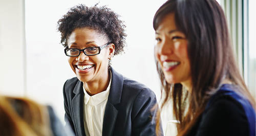 two co-workers smiling looking off camera