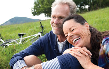 Couple sitting on grassy hill after bike ride